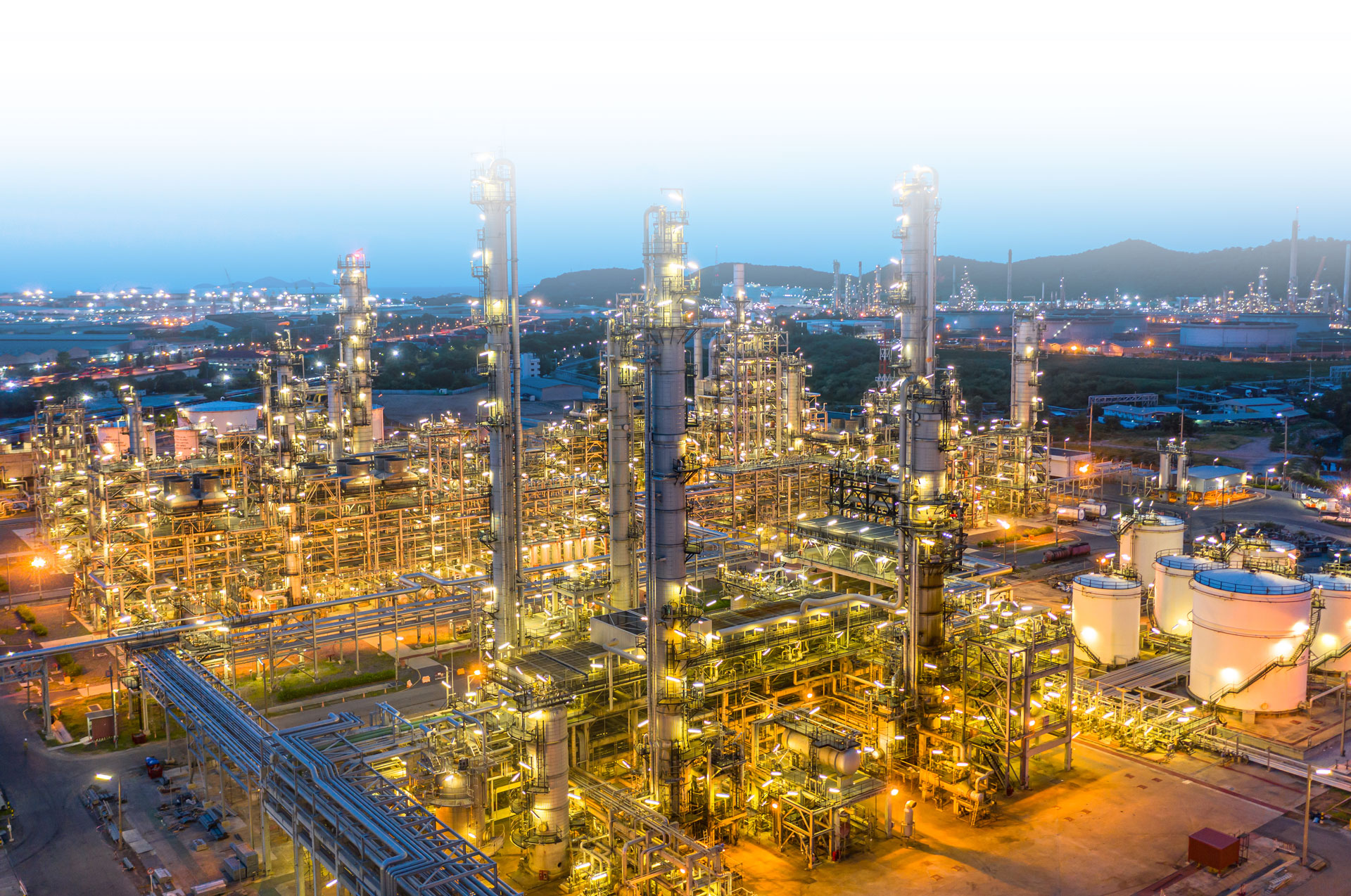 Aerial view of a lit refinery at dusk